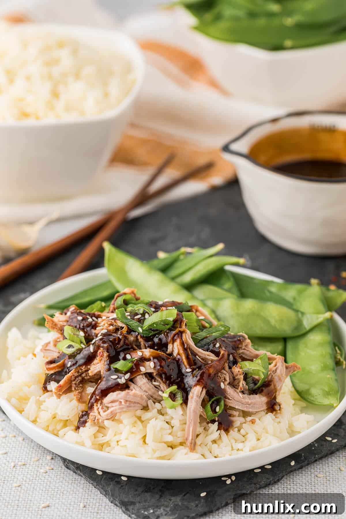Soy Ginger Pork Tenderloin 8 A plate of Asian pork tenderloin served with rice and snow peas, garnished beautifully.