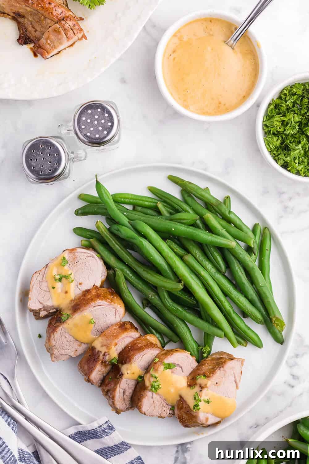 Brown Sugar Dijon Glazed Pork Tenderloin 6 Sliced Brown Sugar Dijon Pork Tenderloin with a side of creamy dipping sauce, ready to be enjoyed.