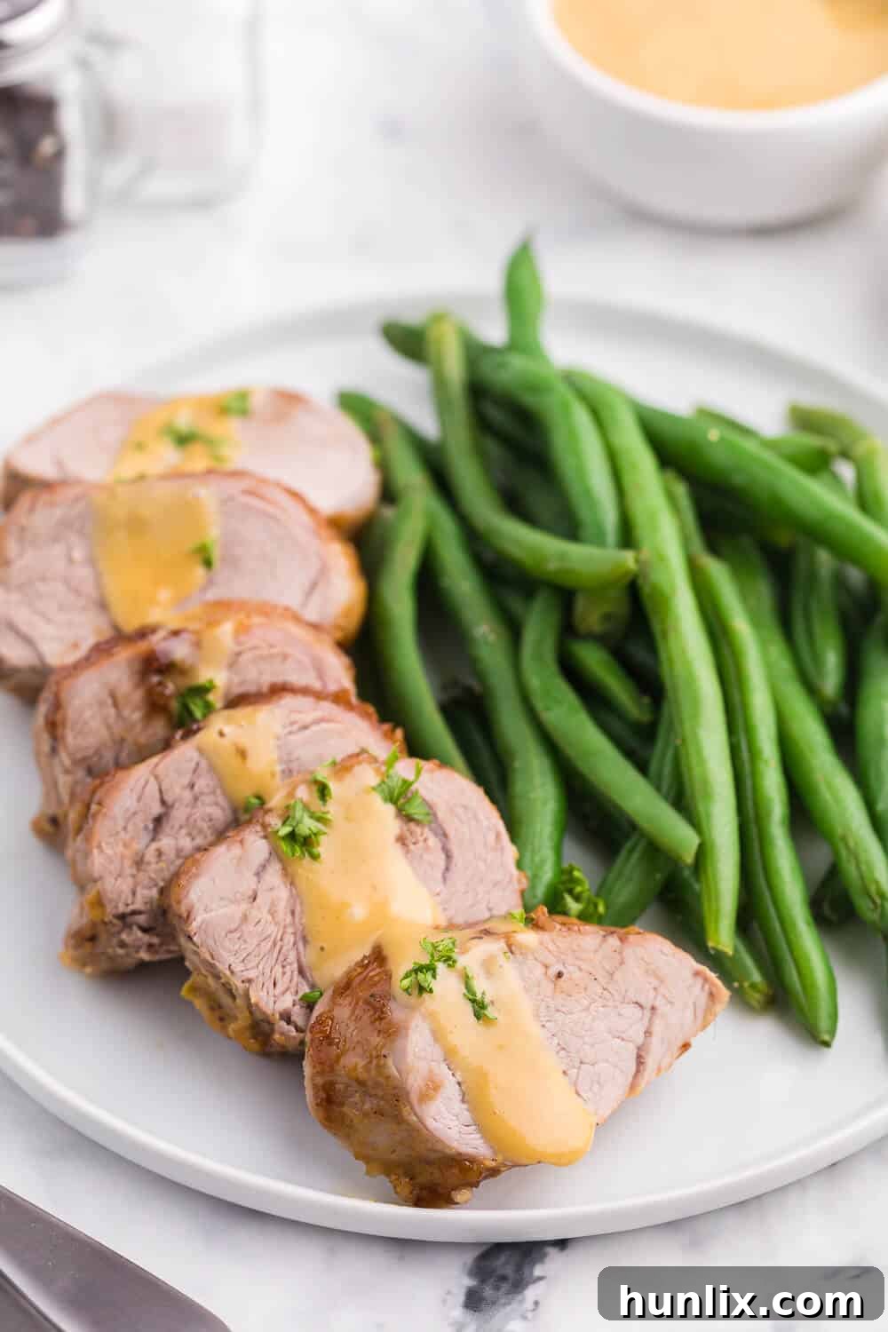 Brown Sugar Dijon Glazed Pork Tenderloin 7 A serving of Brown Sugar Dijon Pork Tenderloin alongside a vibrant green side dish, illustrating a complete and balanced meal.