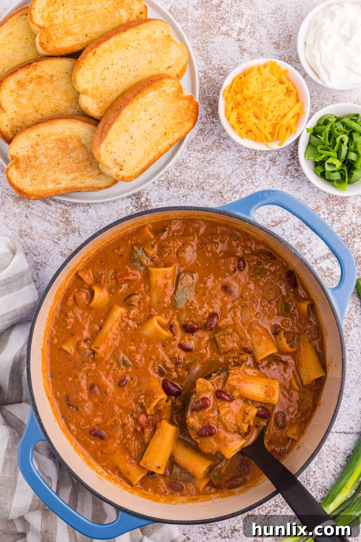 Chili rigatoni in a pot with a ladle.