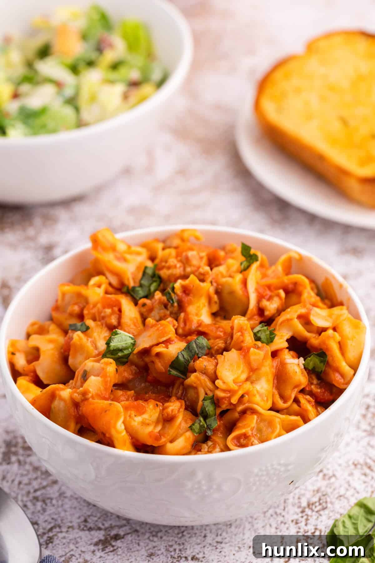 A rustic bowl filled with generous portions of One-Pot Sausage and Cheese Cappelletti, perfectly cheesy and garnished with fresh herbs, inviting diners to dig in.