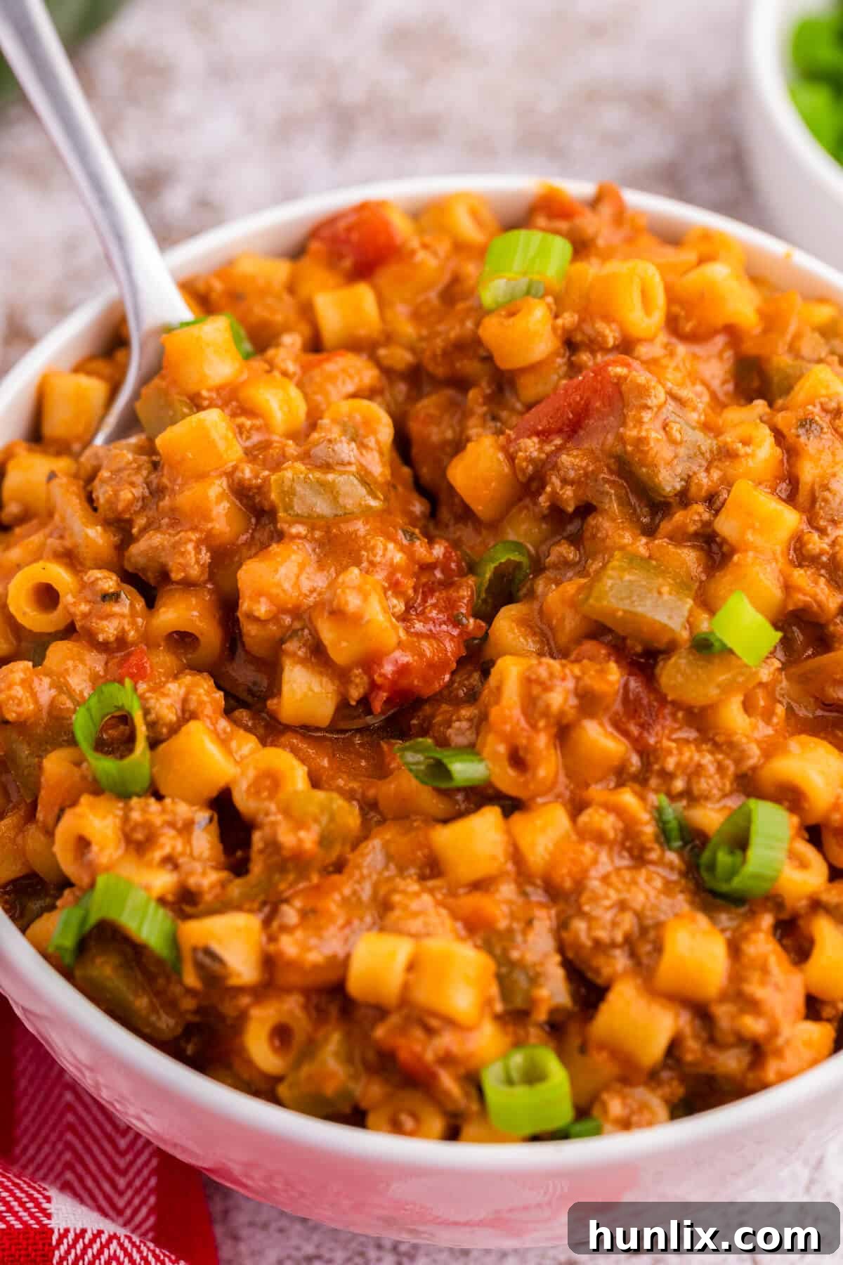 Skillet Stuffed Pepper Pasta 6 A spoon digging into a bowl of creamy unstuffed pepper pasta.