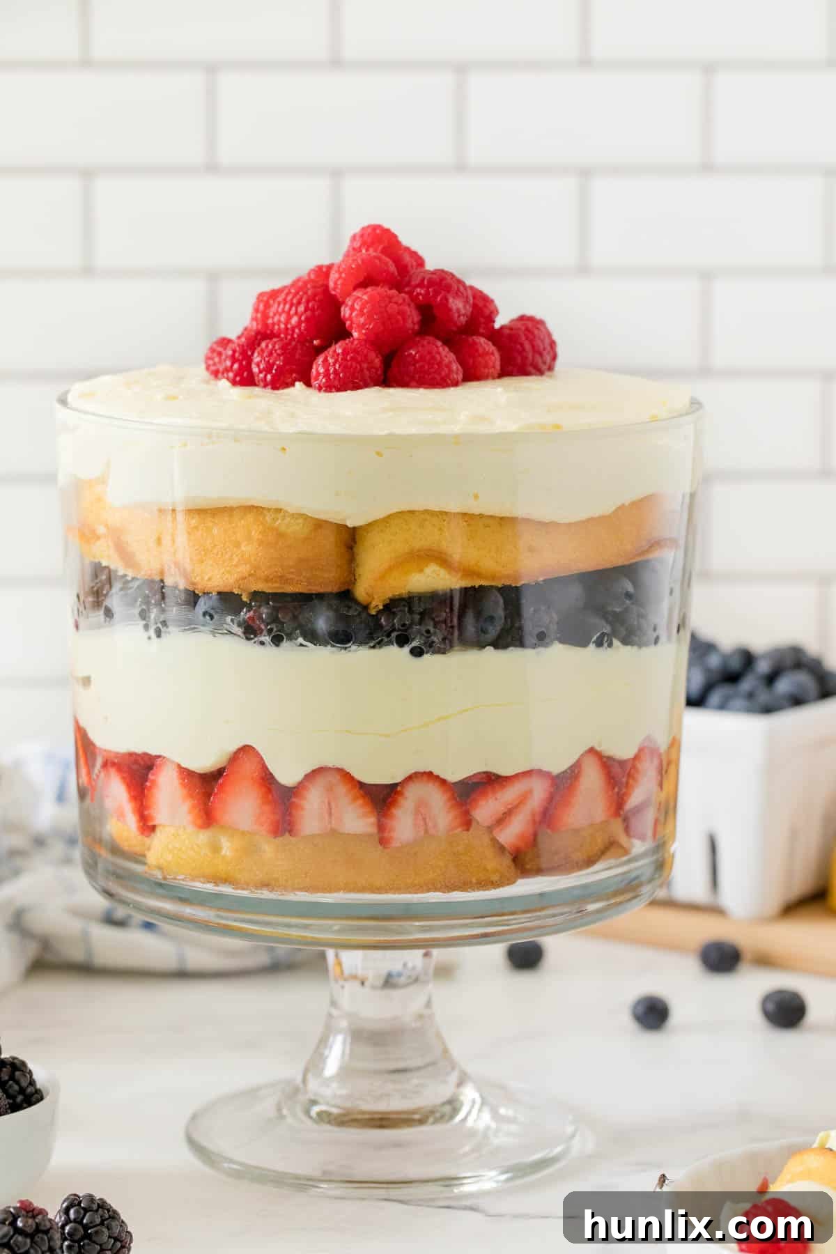 A stunning Berry Cheesecake Trifle layered in a clear trifle dish, showcasing all its colorful layers.