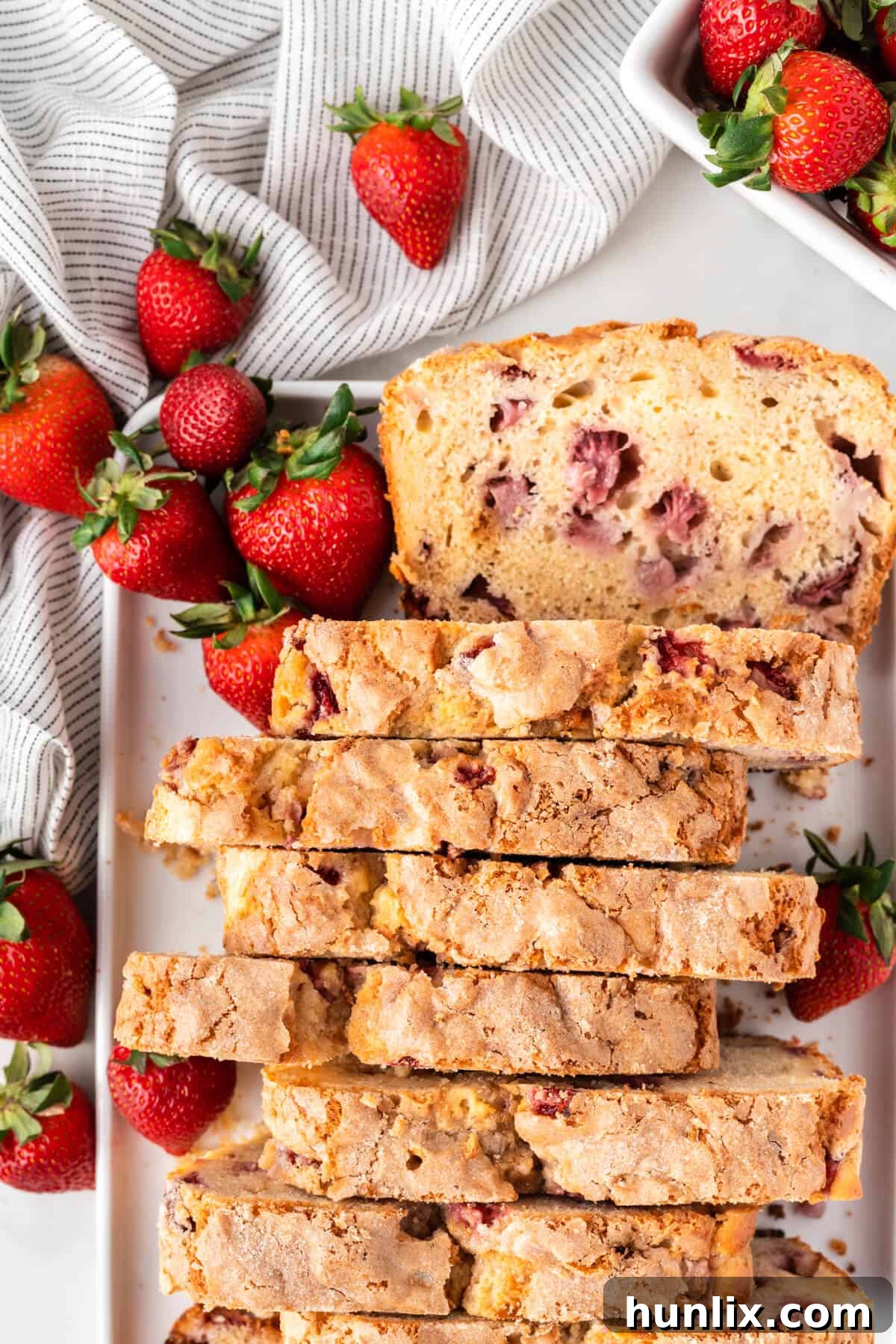 Strawberry Cheesecake Bread 14 A platter of beautifully sliced cream cheese stuffed strawberry bread, with fresh berries scattered around, ready for serving.