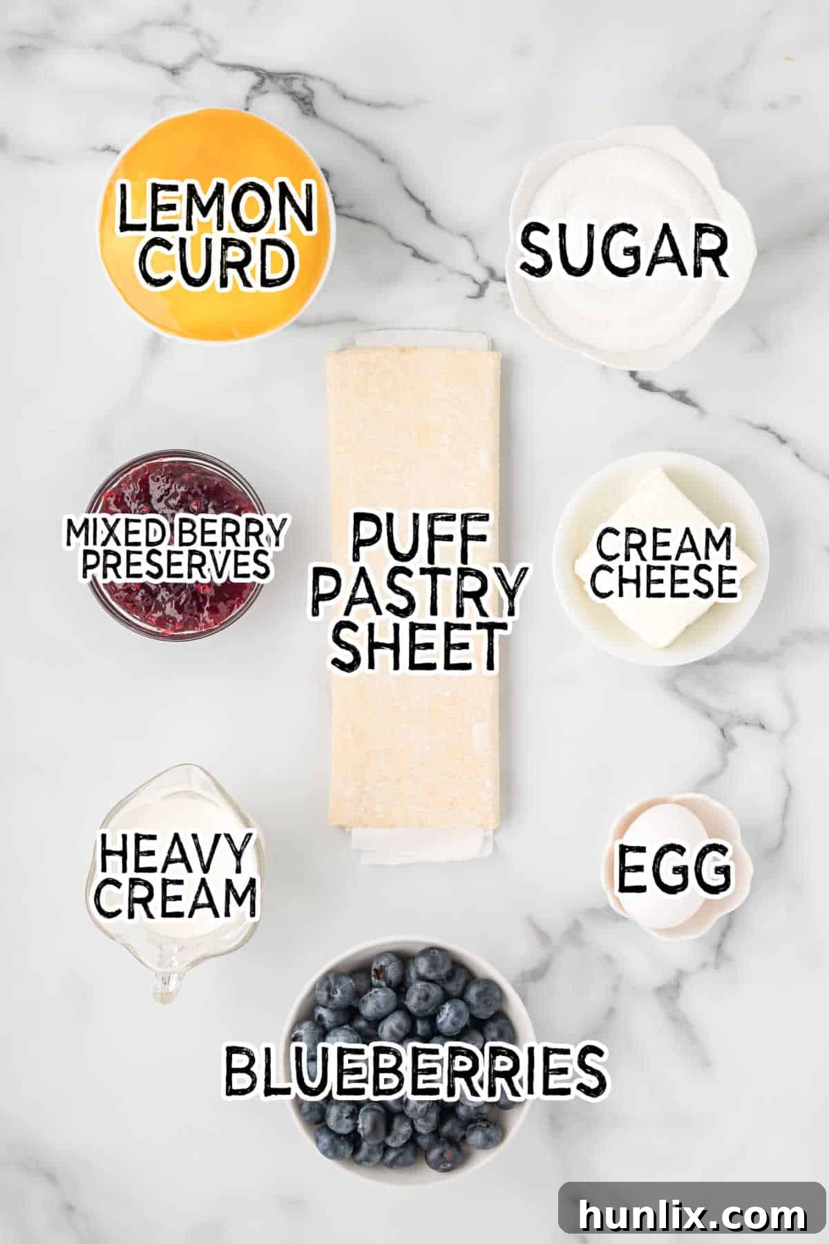 Fresh ingredients for blueberry lemon tart including puff pastry, lemons, blueberries, and cream cheese.