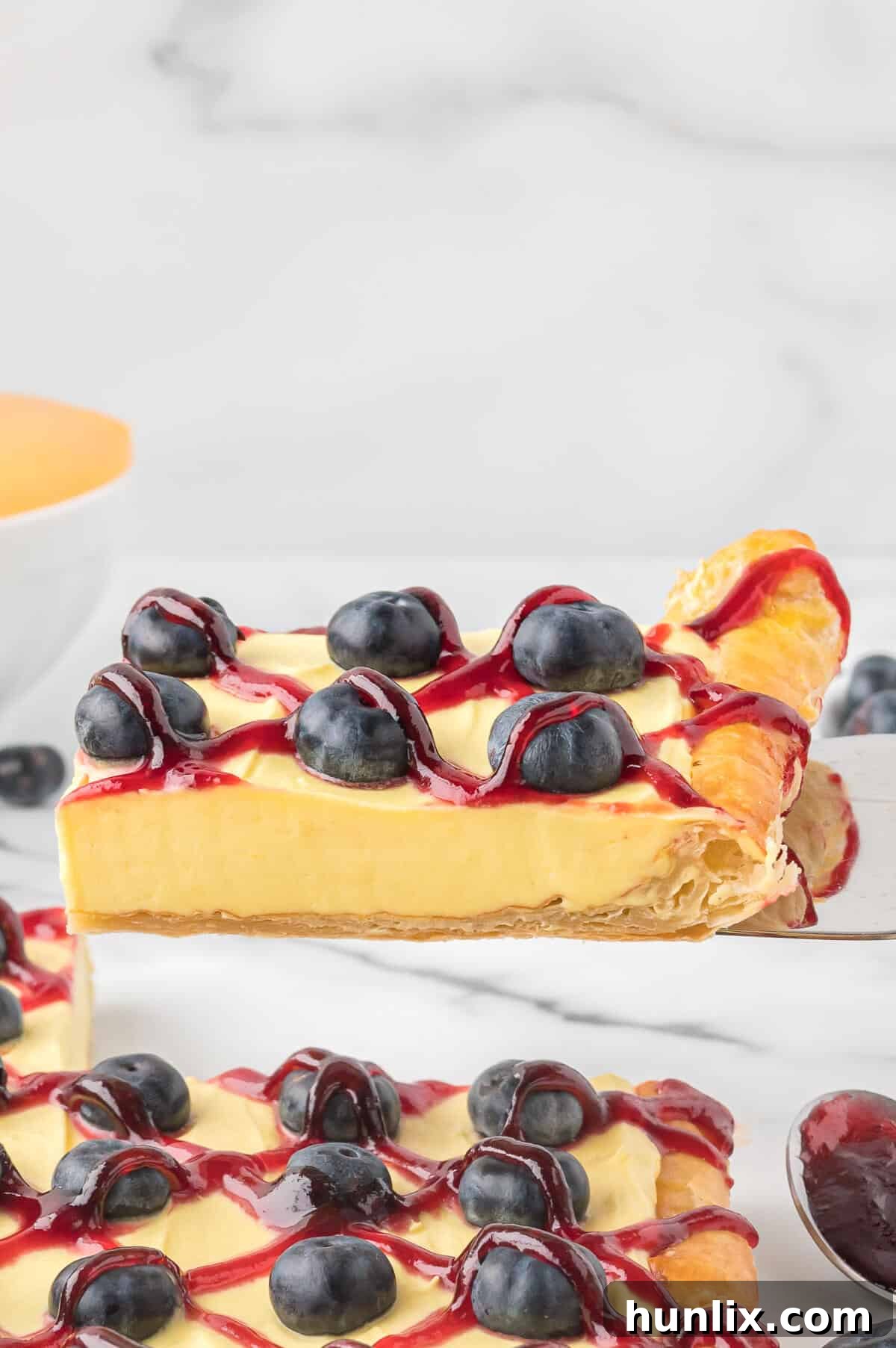 A perfectly sliced piece of blueberry lemon tart on a serving spatula, ready to be enjoyed.