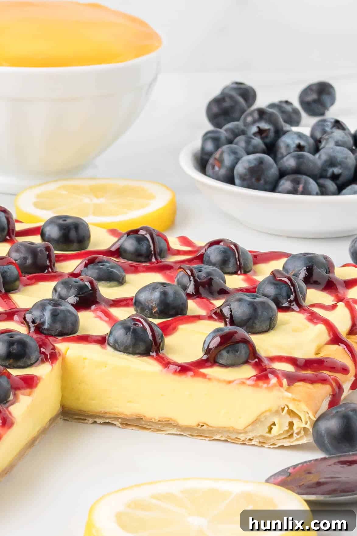 A blueberry lemon tart with one slice removed, showcasing its layers.