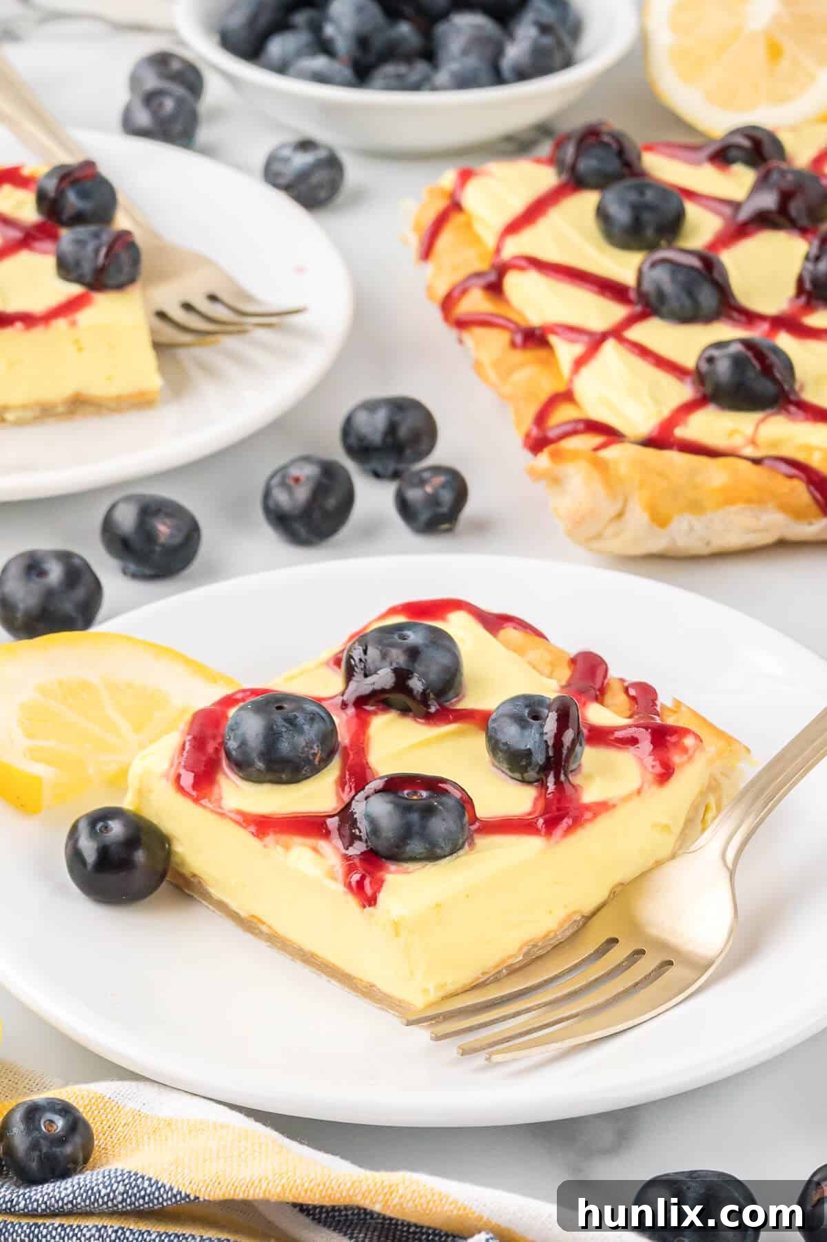 A delectable slice of blueberry lemon tart served on a plate with a fork, ready to be enjoyed.