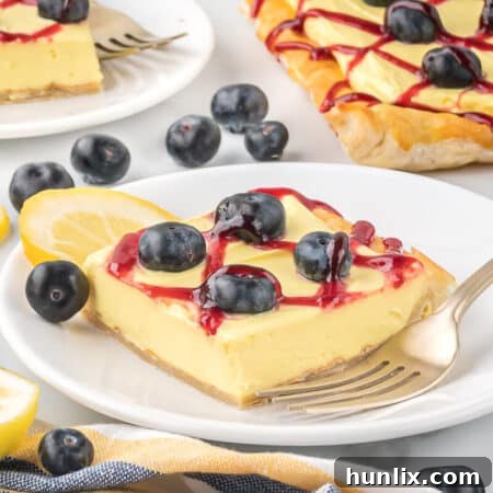A slice of blueberry lemon tart on a plate with a fork.