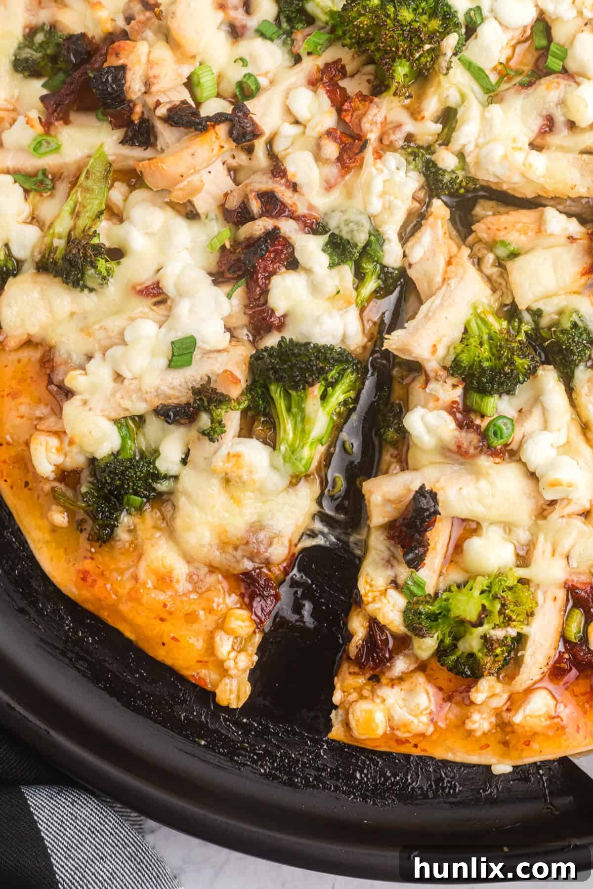 A pan of sweet chili chicken thai pizza with slices cut.