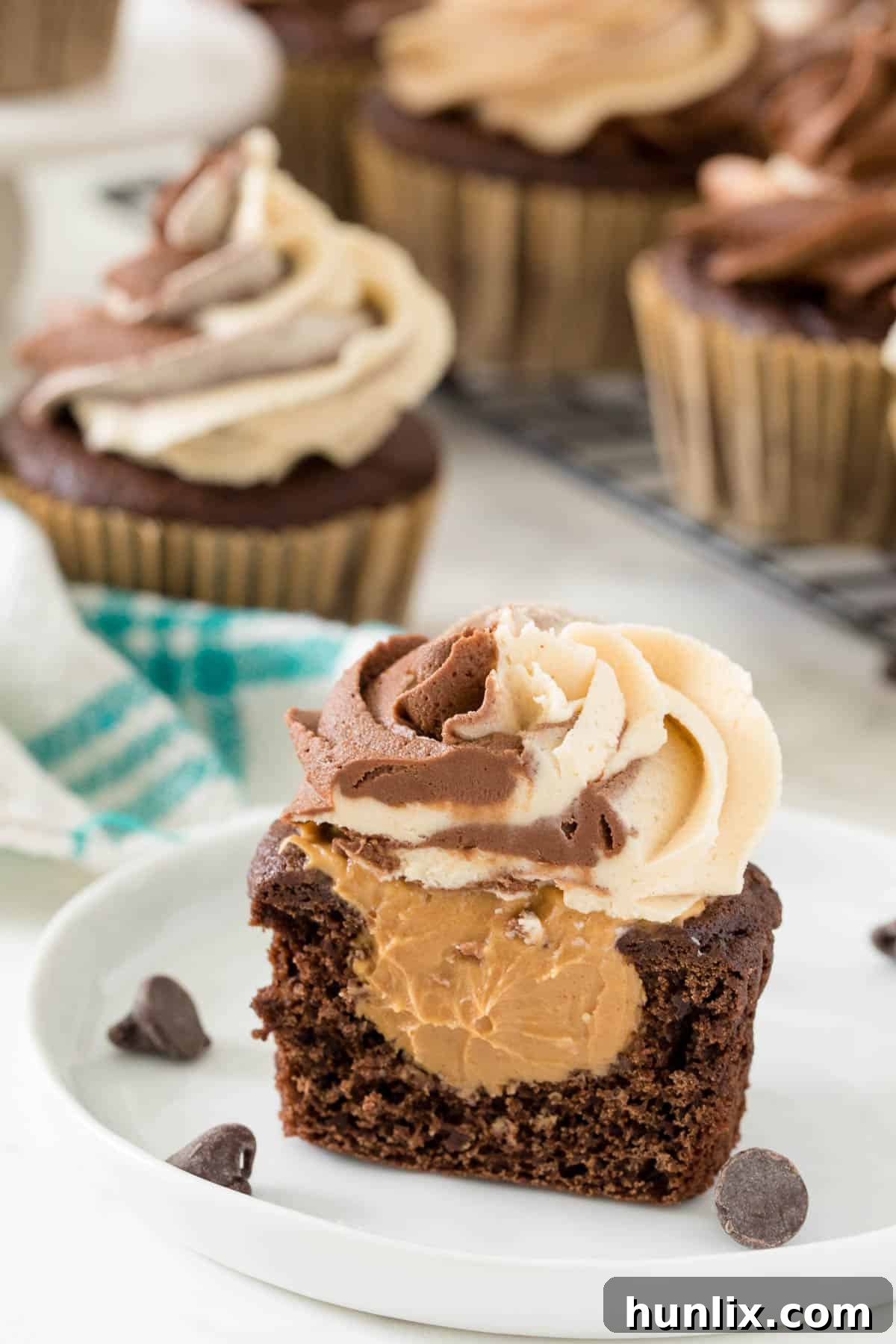 A chocolate peanut butter cupcake cut in half on a white plate, revealing the creamy peanut butter filling inside.