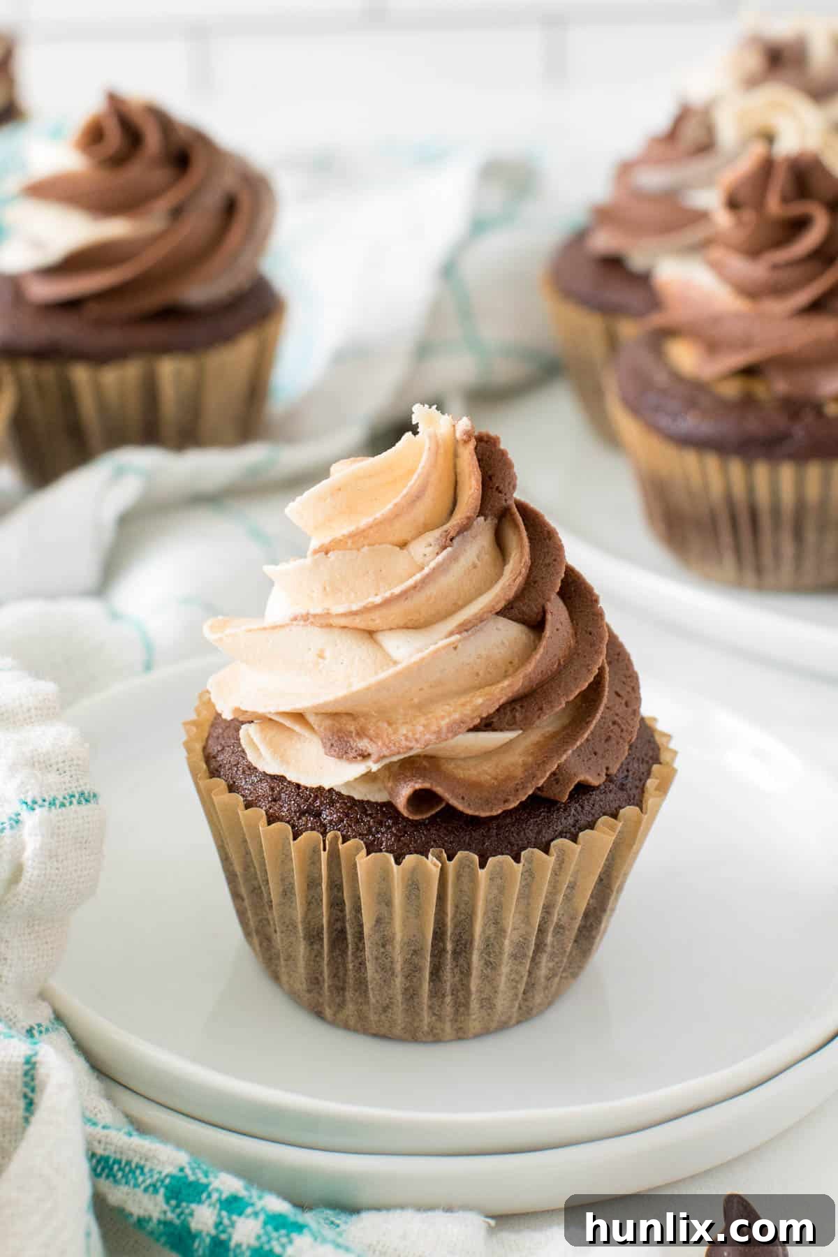 A single chocolate peanut butter cupcake on a white plate, showcasing its fluffy frosting and rich color.