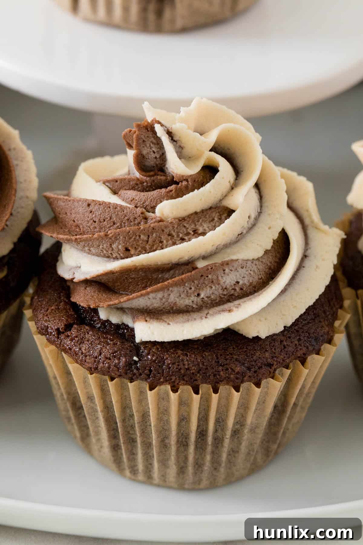 A beautifully frosted chocolate peanut butter cupcake showcased on a cupcake stand, ready to be enjoyed.