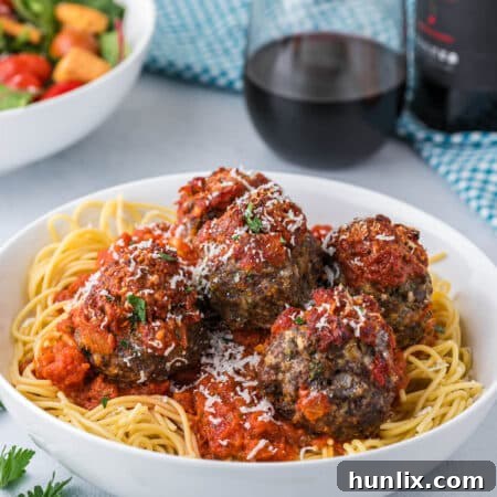 Cheesy meatballs and spaghetti in a bowl.