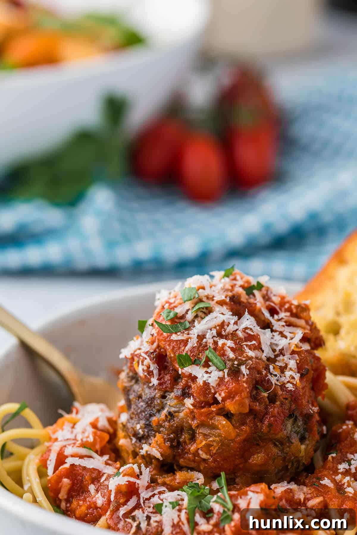 A comforting bowl of cheesy meatballs served with spaghetti and rich tomato sauce.