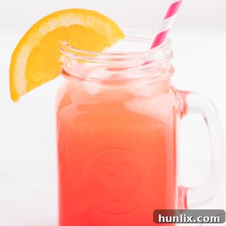 The finished Shirley Temple drink in a glass mug with a straw and an orange slice for garnish.
