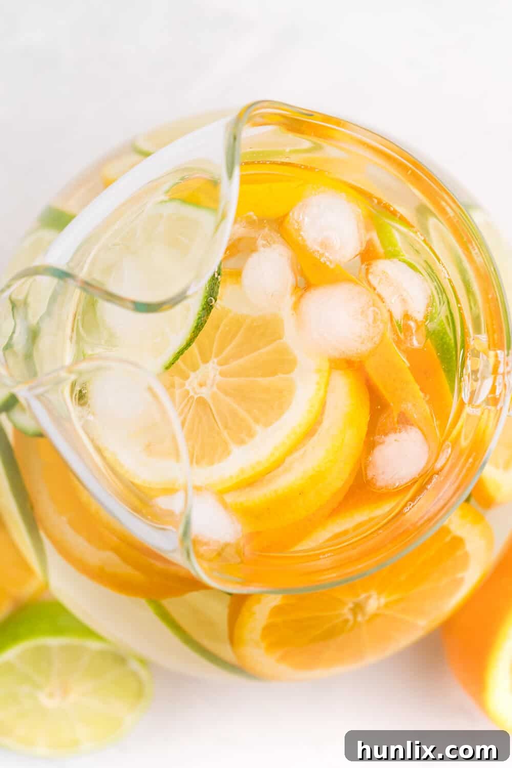 An overhead shot of a glass pitcher filled with refreshing citrus-infused water, featuring sliced lemons, limes, and oranges.
