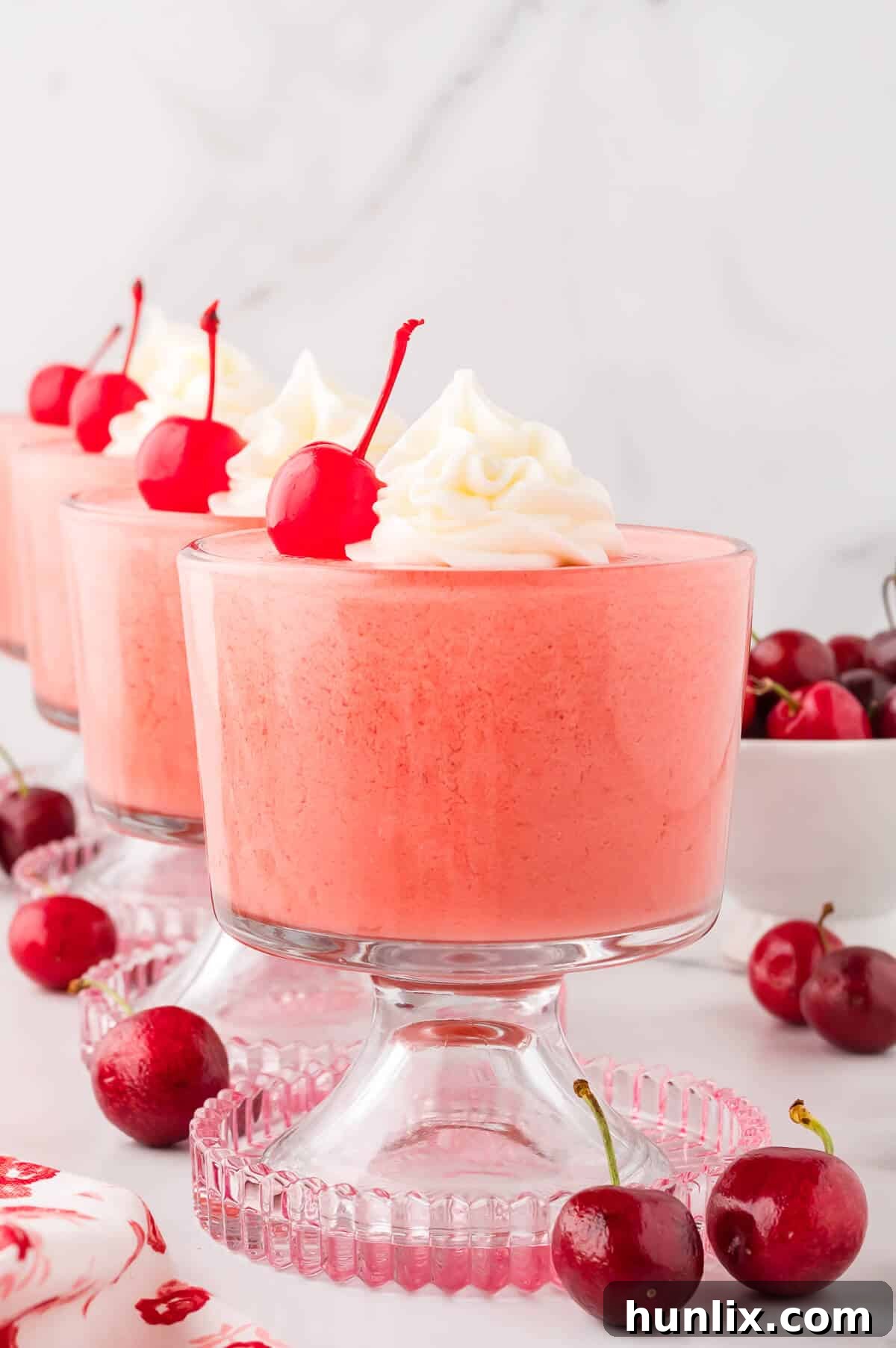 Velvet Cherry Dream 6 A close-up of cherry mousse in a parfait dish, showing its smooth texture and a fresh cherry garnish.