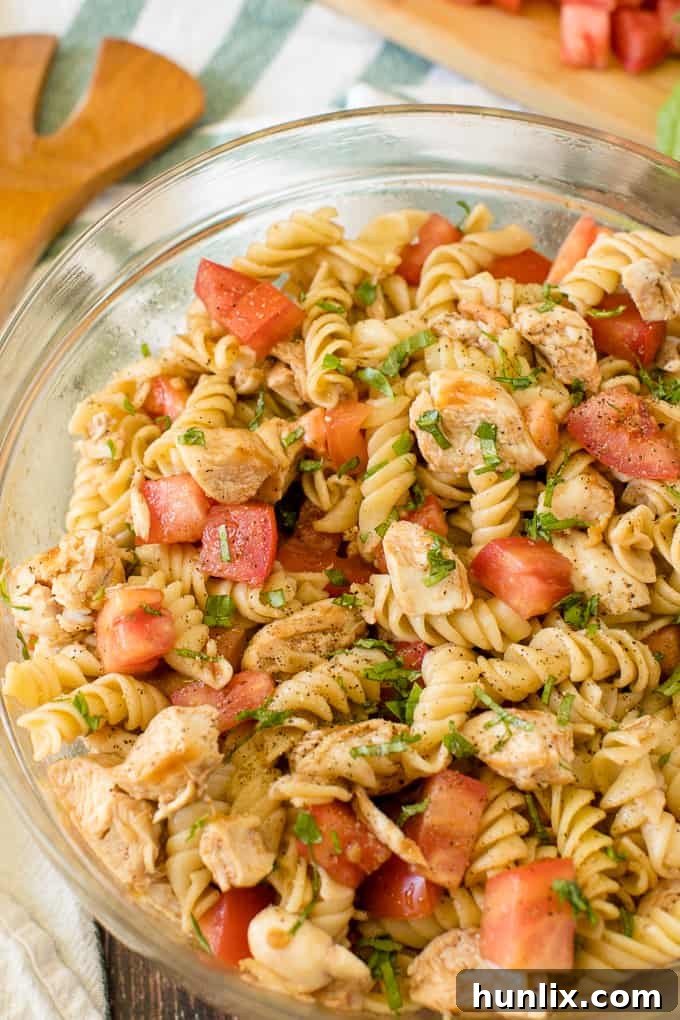 Close-up of Bruschetta Chicken Pasta Salad showcasing tender chicken pieces, pasta, and fresh ingredients.