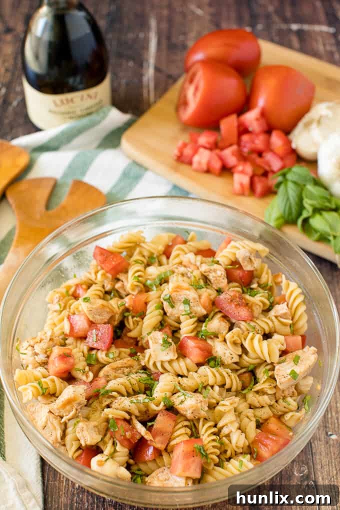A large bowl of Bruschetta Chicken Pasta Salad, ready to be served at a gathering.