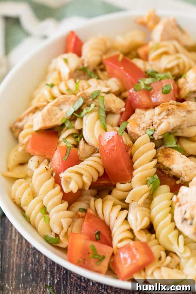 Final presentation of Bruschetta Chicken Pasta Salad in a rustic bowl with fresh garnishes.