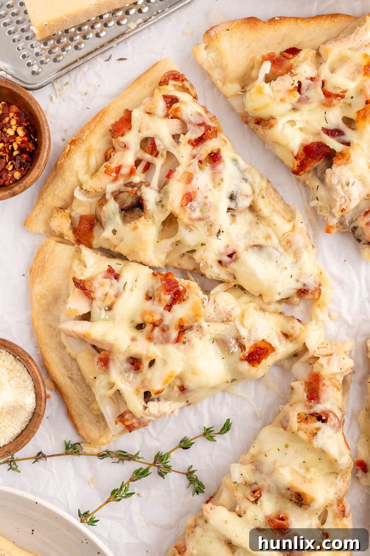 Multiple slices of freshly baked Chicken Bacon Alfredo Pizza, each slice featuring a golden crust, rich white sauce, and a medley of chicken, bacon, mushrooms, and melted mozzarella.