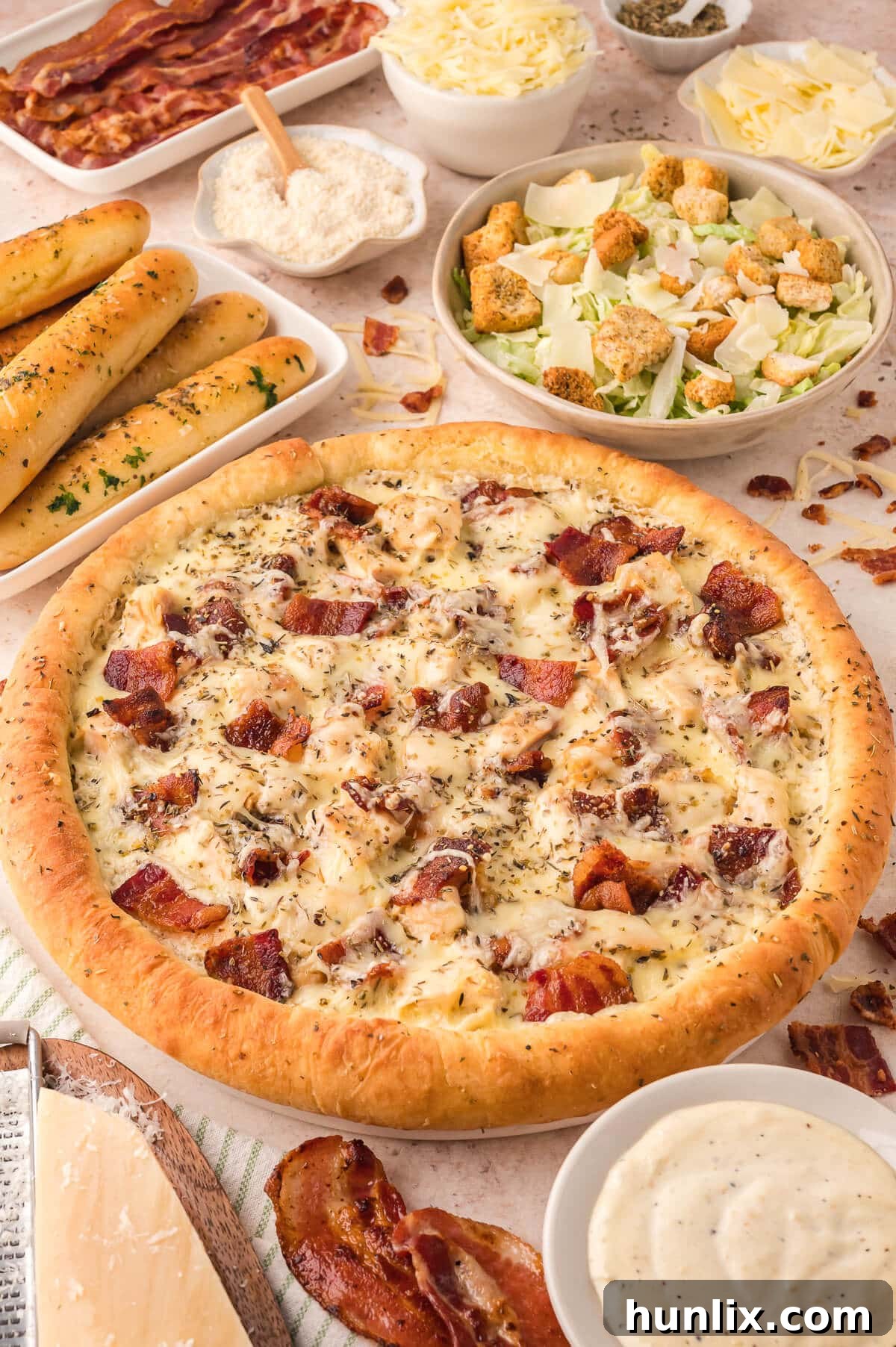 Signature Chicken Caesar Pizza 2 Golden-crusted Chicken Caesar Pizza topped with chicken, bacon, cheese, and a creamy Caesar dressing swirl, surrounded by fresh ingredients.