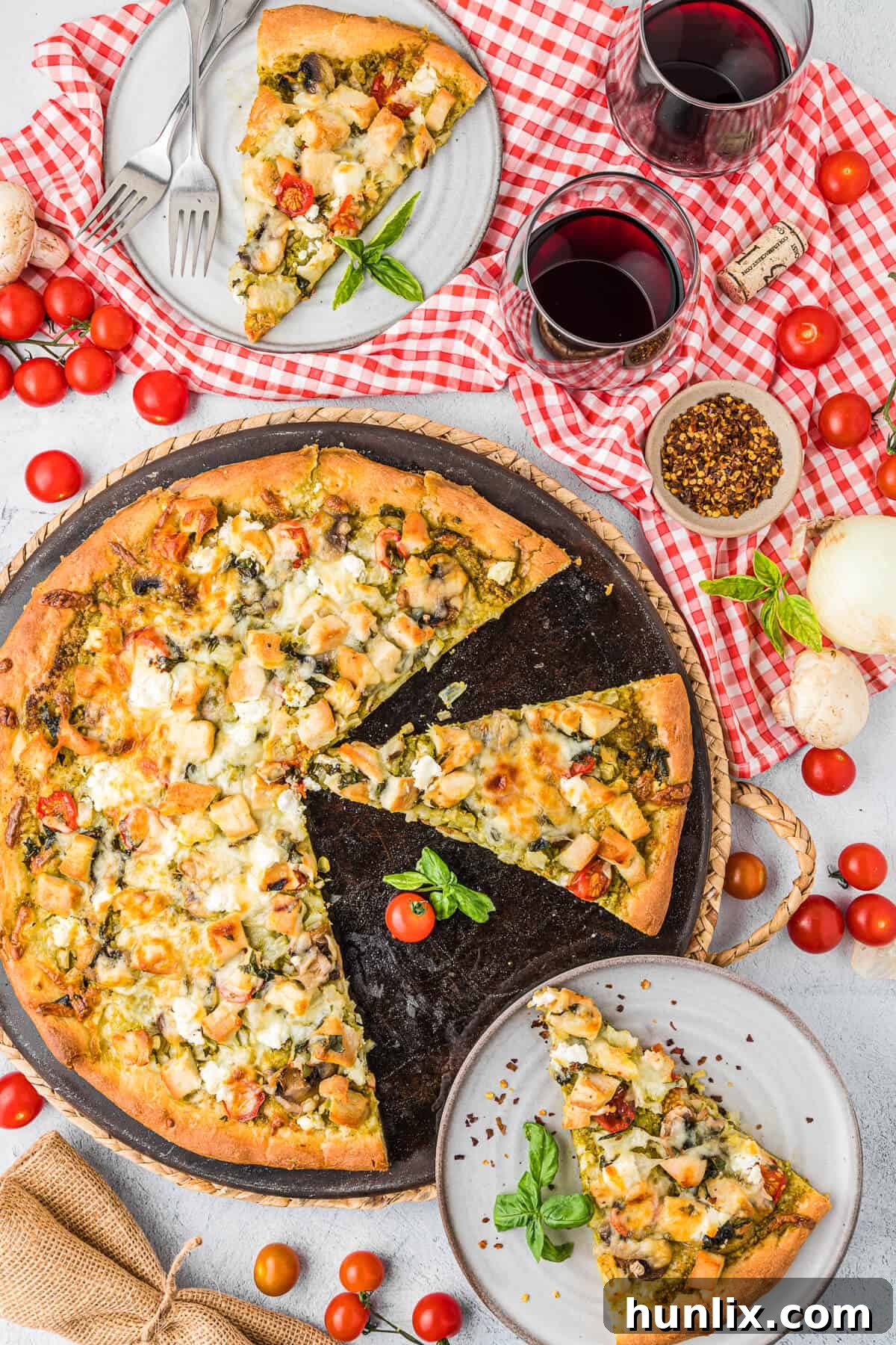 A chicken pesto pizza on a pan with several slices already cut and some removed, showing the golden crust and melted cheese.