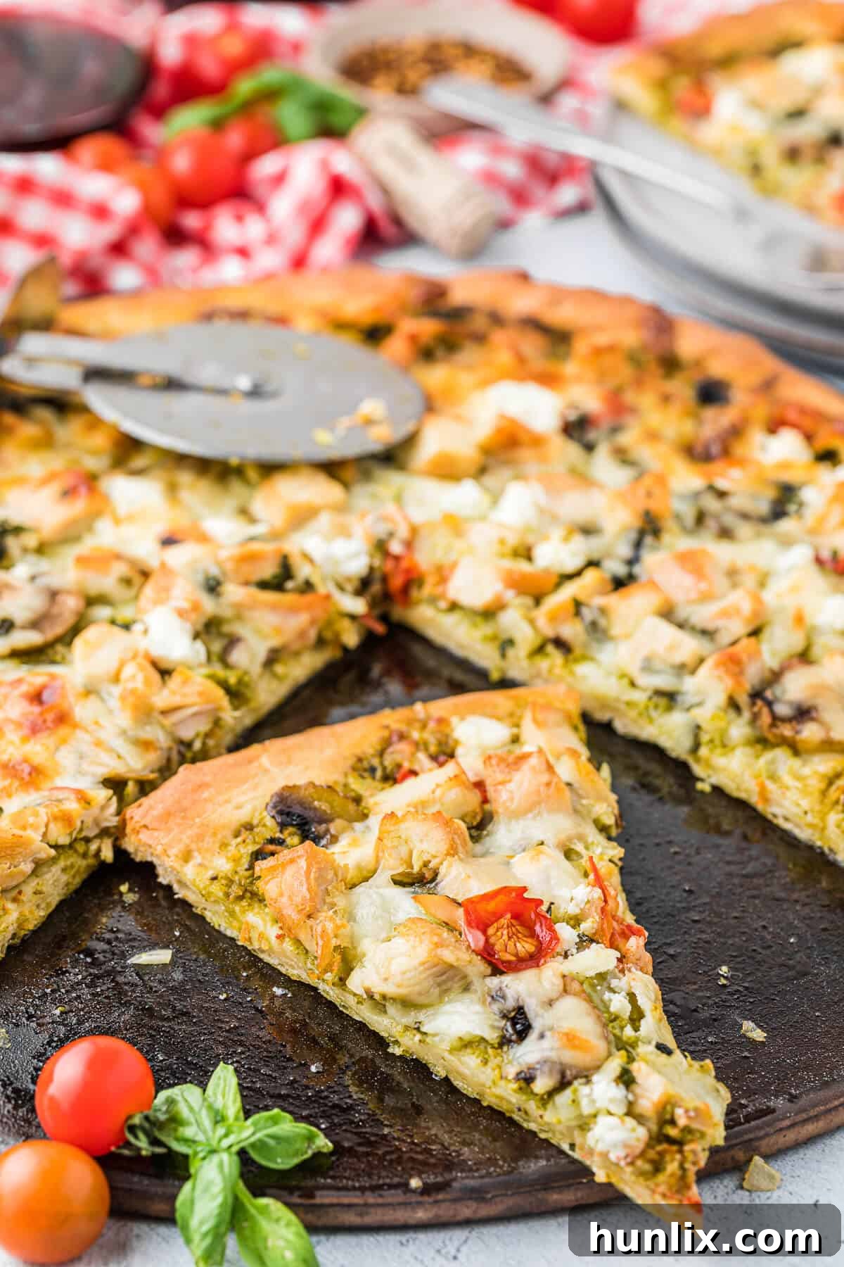 Several slices of chicken pesto pizza arranged on a pizza pan, showing the rich toppings and golden crust.