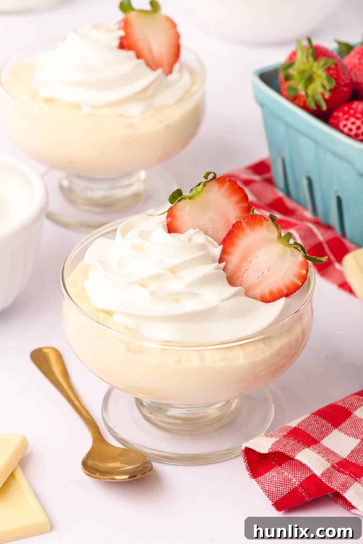 White chocolate pudding in a elegant parfait dish, garnished with fresh strawberries and whipped cream.