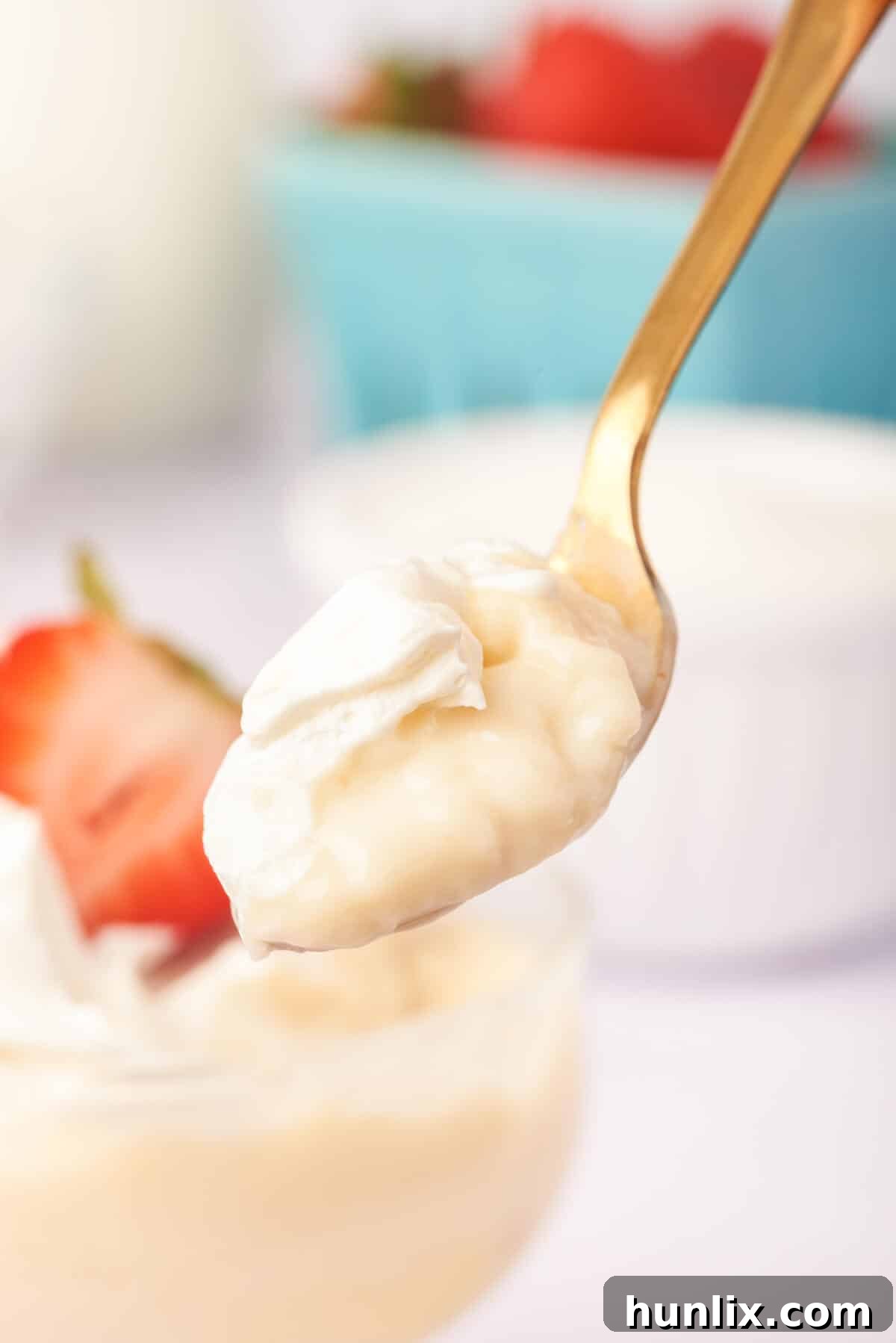 A close-up of a spoon scooping into creamy white chocolate pudding, highlighting its smooth texture.