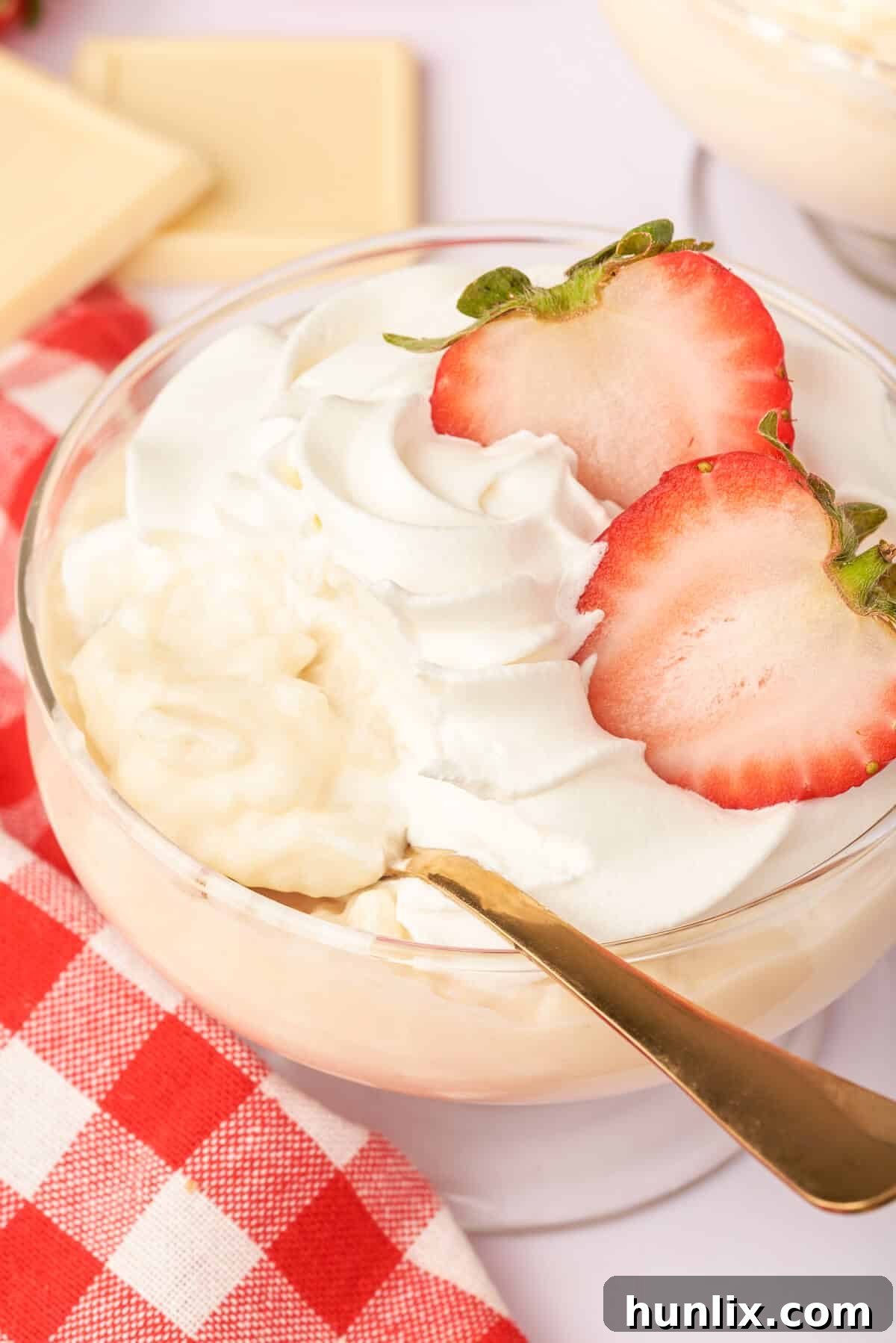 A beautiful parfait dish filled with layers of white chocolate pudding, topped with strawberries and whipped cream.