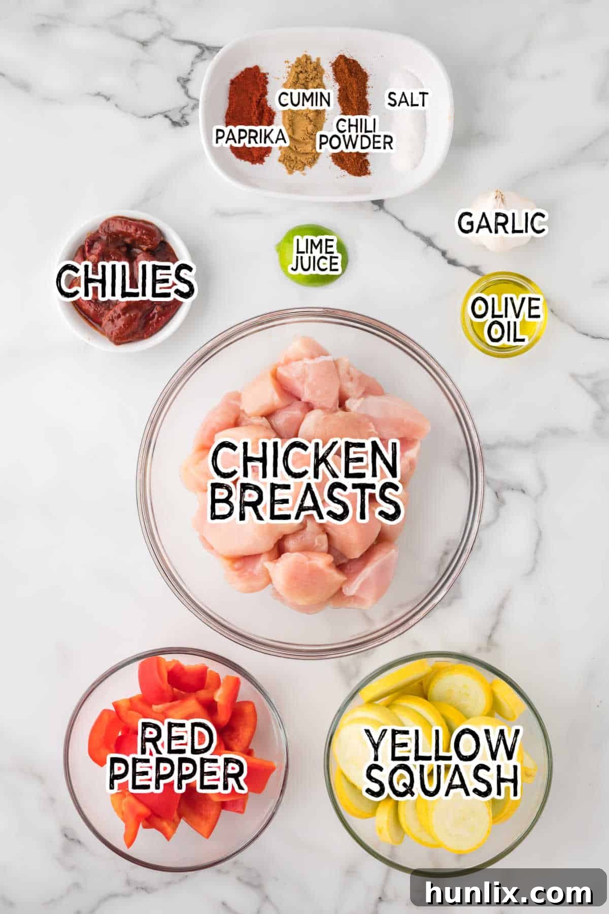 Fresh ingredients laid out to prepare chipotle chicken skewers, including chicken, peppers, squash, and spices.