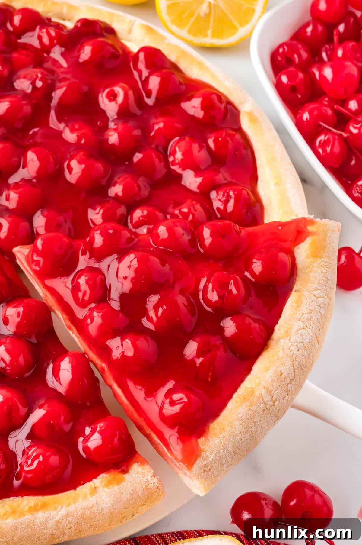 A slice of cherry cheesecake pizza on a spatula, showcasing its layers.