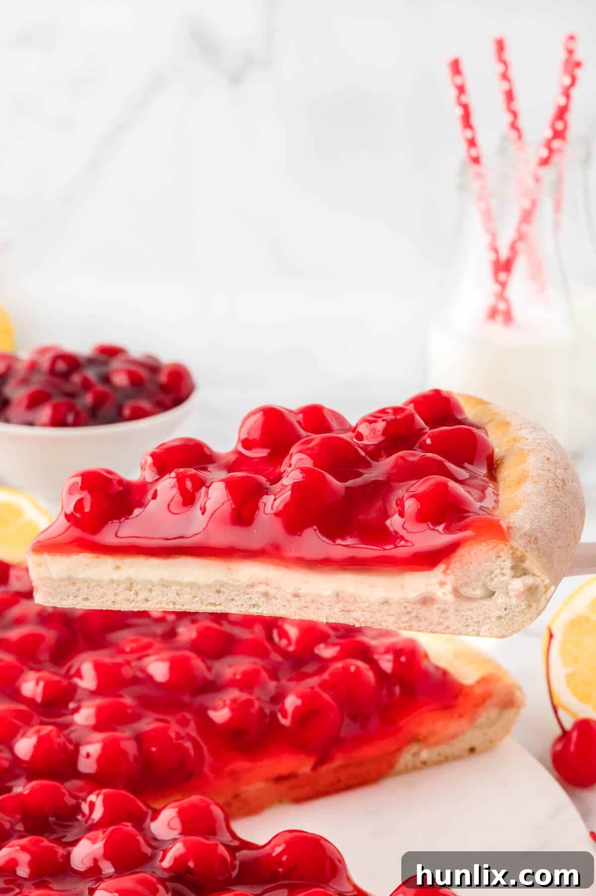 A perfectly sliced piece of cherry cheesecake pizza resting on a serving spatula.