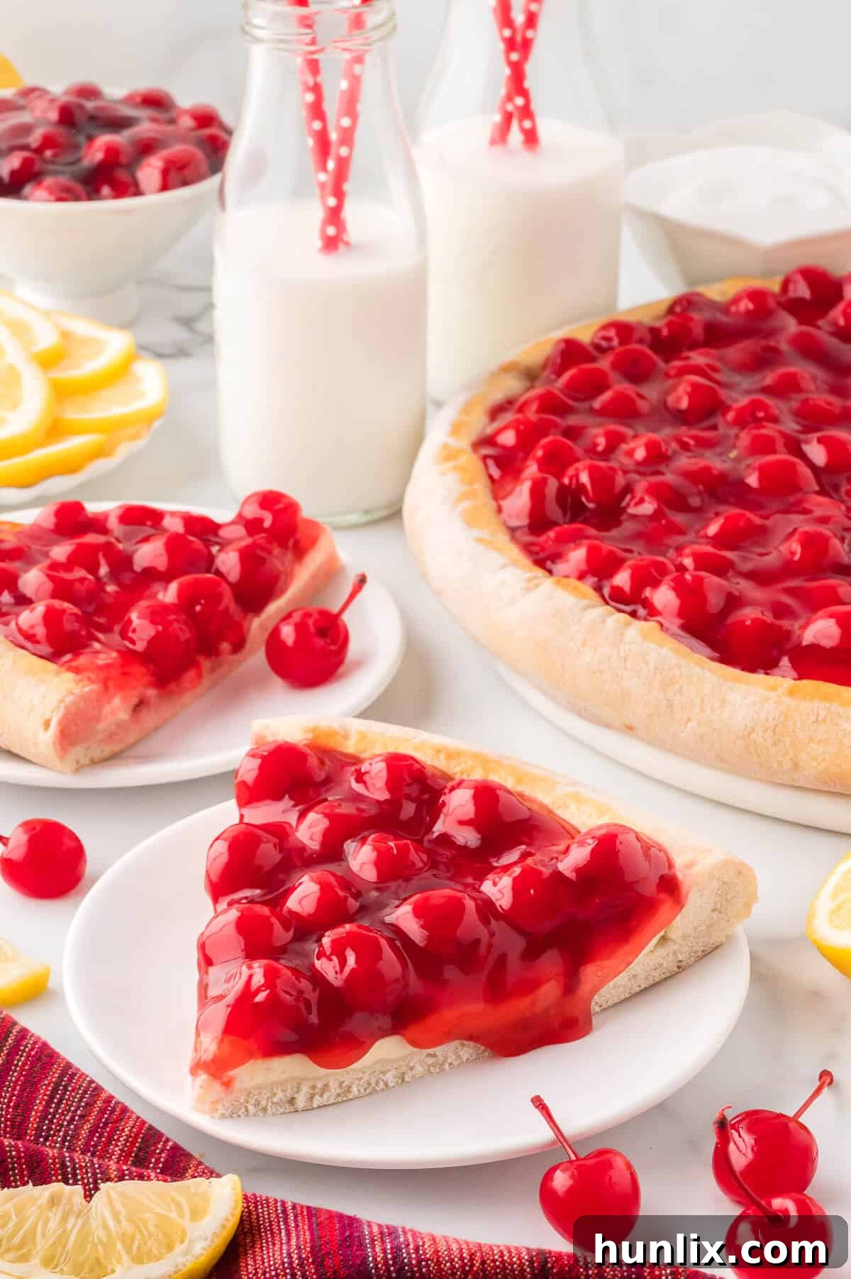 A generous slice of cherry cheesecake pizza served on a white plate, ready to eat.