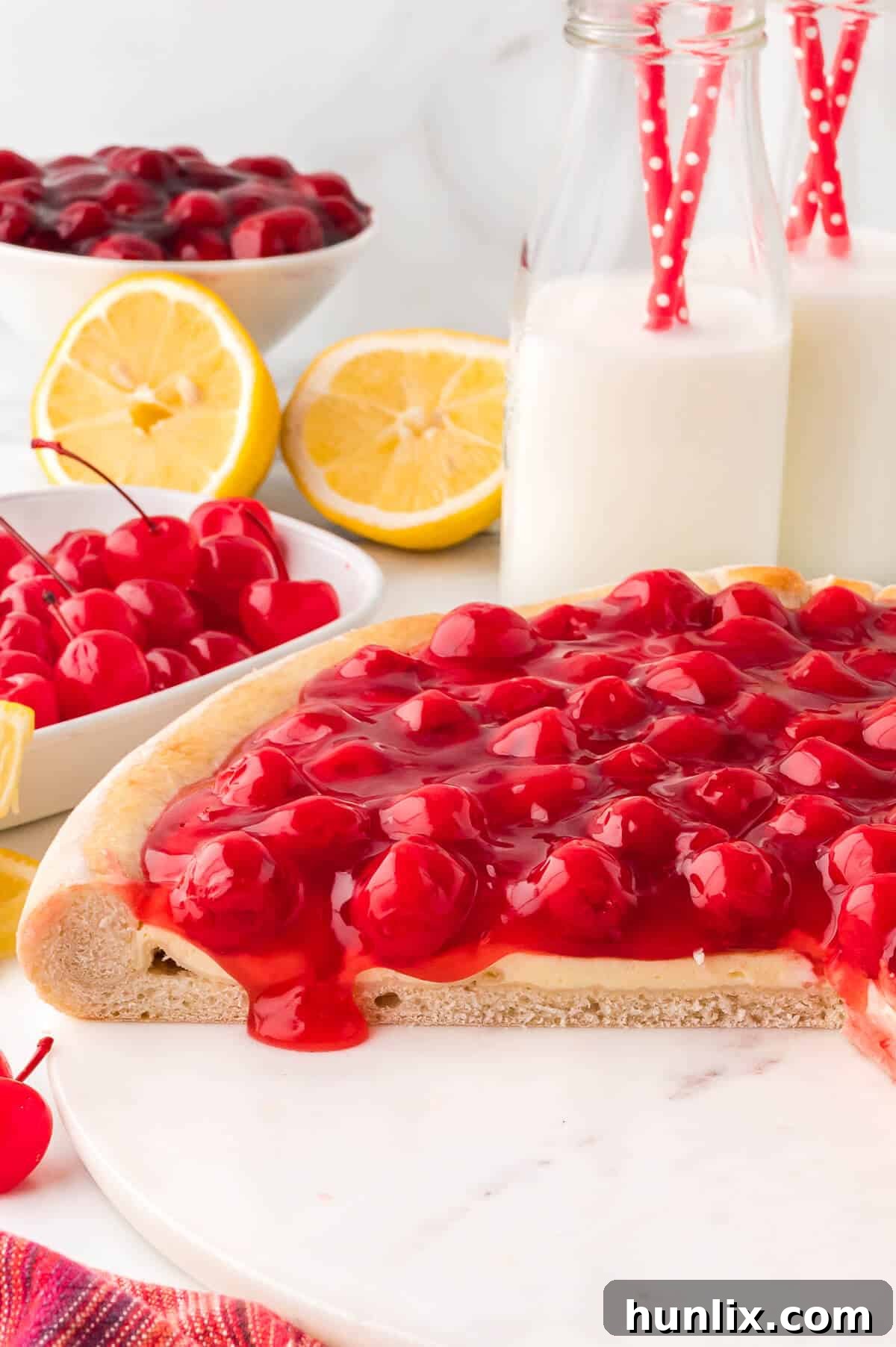 A whole cherry cheesecake pizza with several slices already cut and removed, showing the perfect texture.