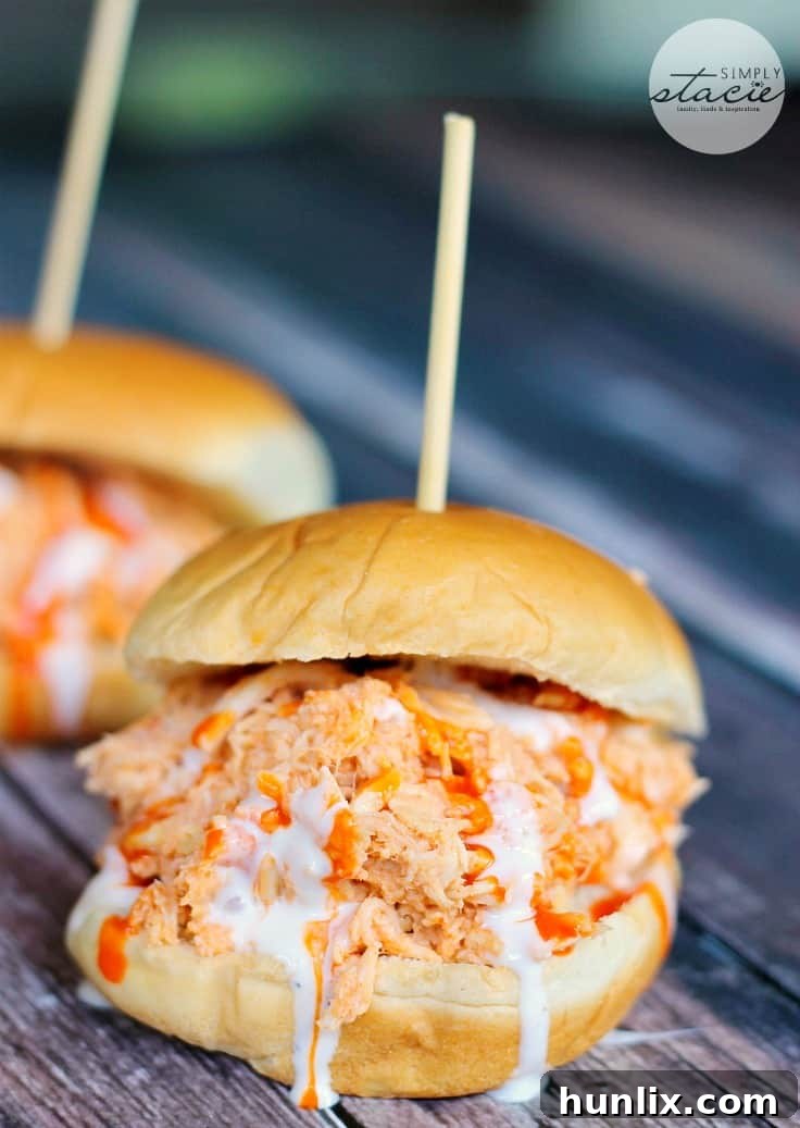 Tender, slow-cooked Buffalo Chicken Sliders on a bun, topped with Ranch dressing – the ultimate game day appetizer.