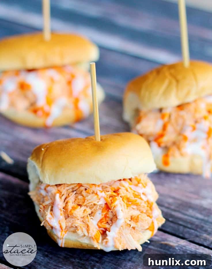 Arrangement of Slow Cooker Buffalo Chicken Sliders, garnished with fresh herbs and ranch, ready for serving.