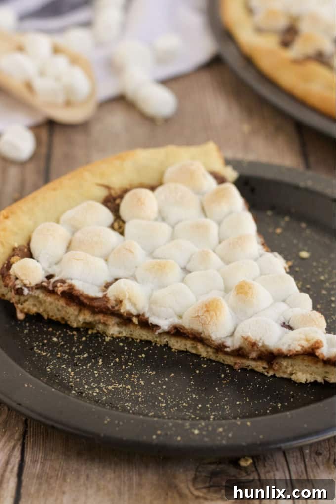 Gooey Smores Dessert Pizza 6 A baker's hands slicing a fresh S'mores Pizza with a pizza cutter, showcasing the soft marshmallows and melted chocolate.