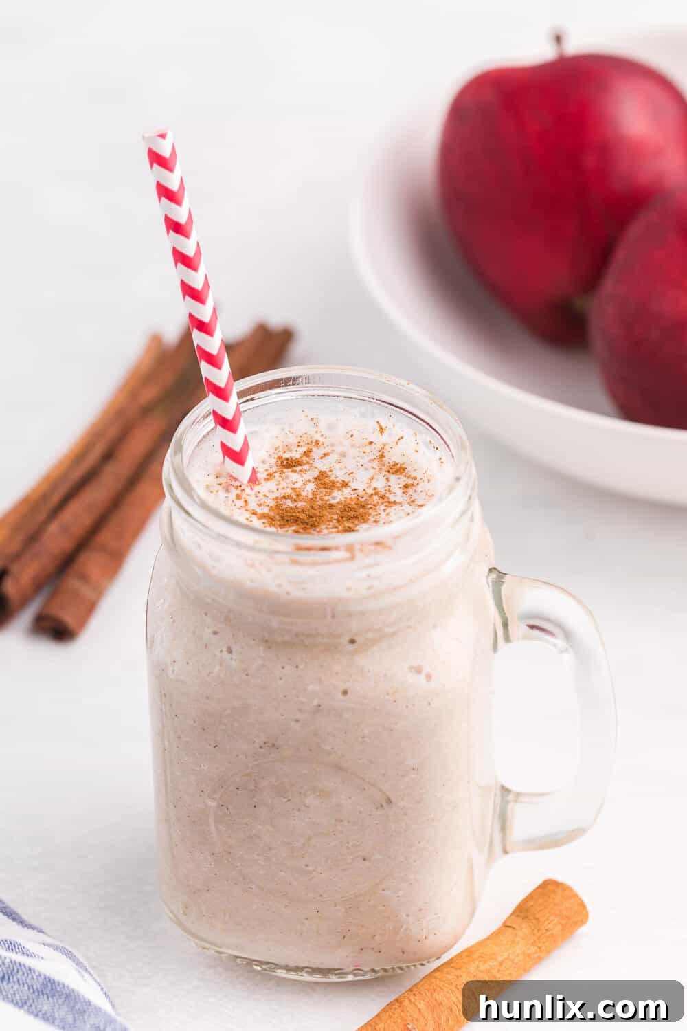 Autumn Spiced Apple Blend 2 A creamy Apple Spice Smoothie on a white surface, garnished with cinnamon.