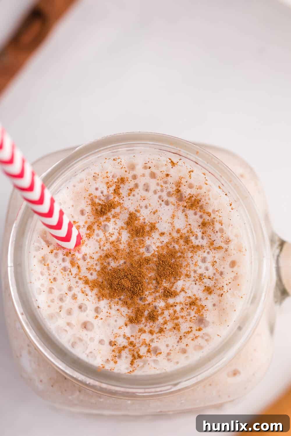 Autumn Spiced Apple Blend 4 A close-up of the Apple Spice Smoothie in a glass with a striped straw, showing the texture and cinnamon garnish.