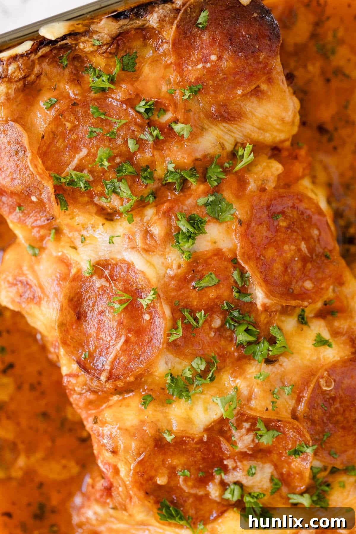 A pan of golden-brown pizza stuffed chicken, ready to be served, showcasing melted cheese and pepperoni.