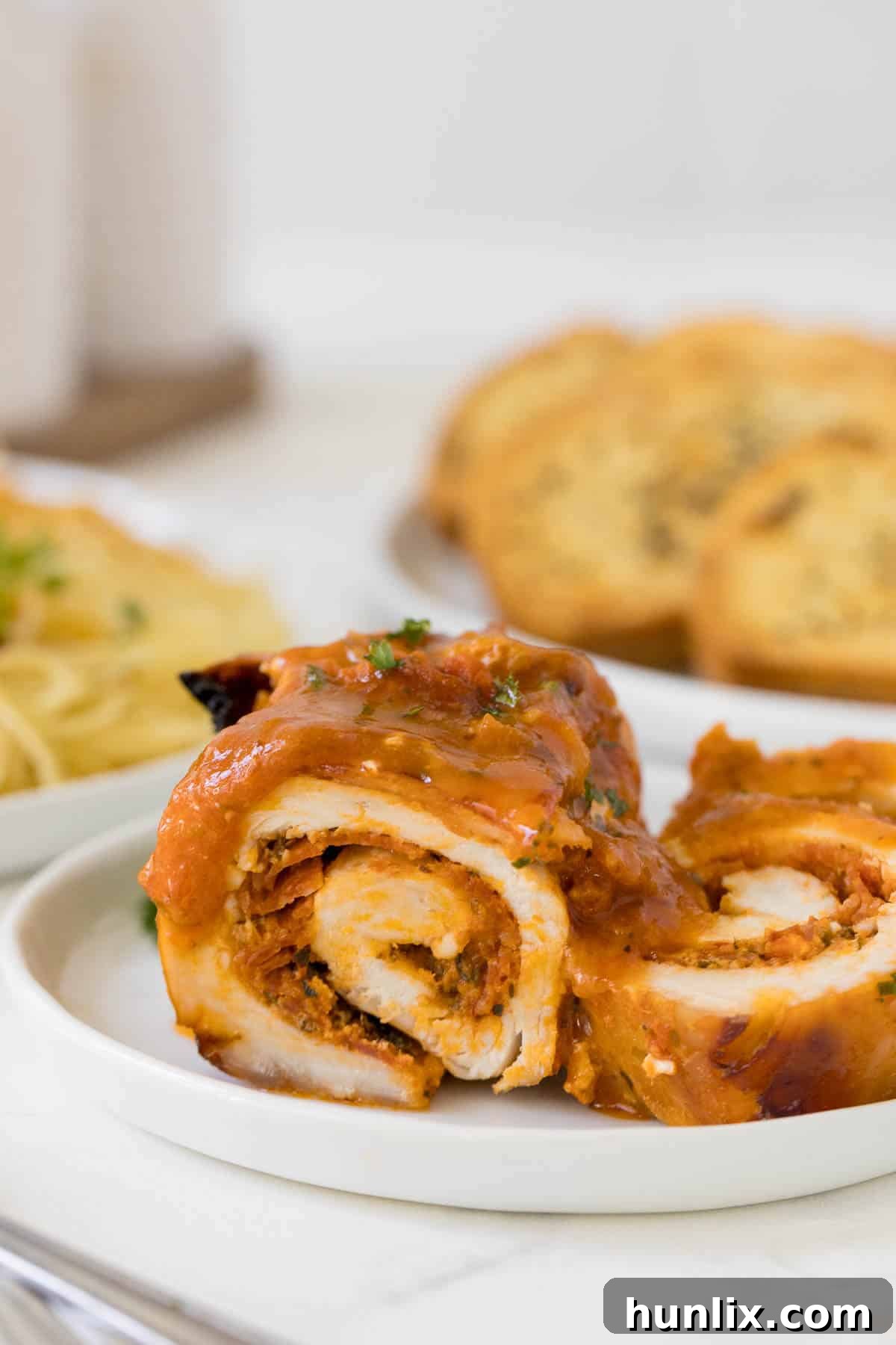 A piece of pizza stuffed chicken, perfectly cut in half to reveal the cheesy, pepperoni-filled interior.