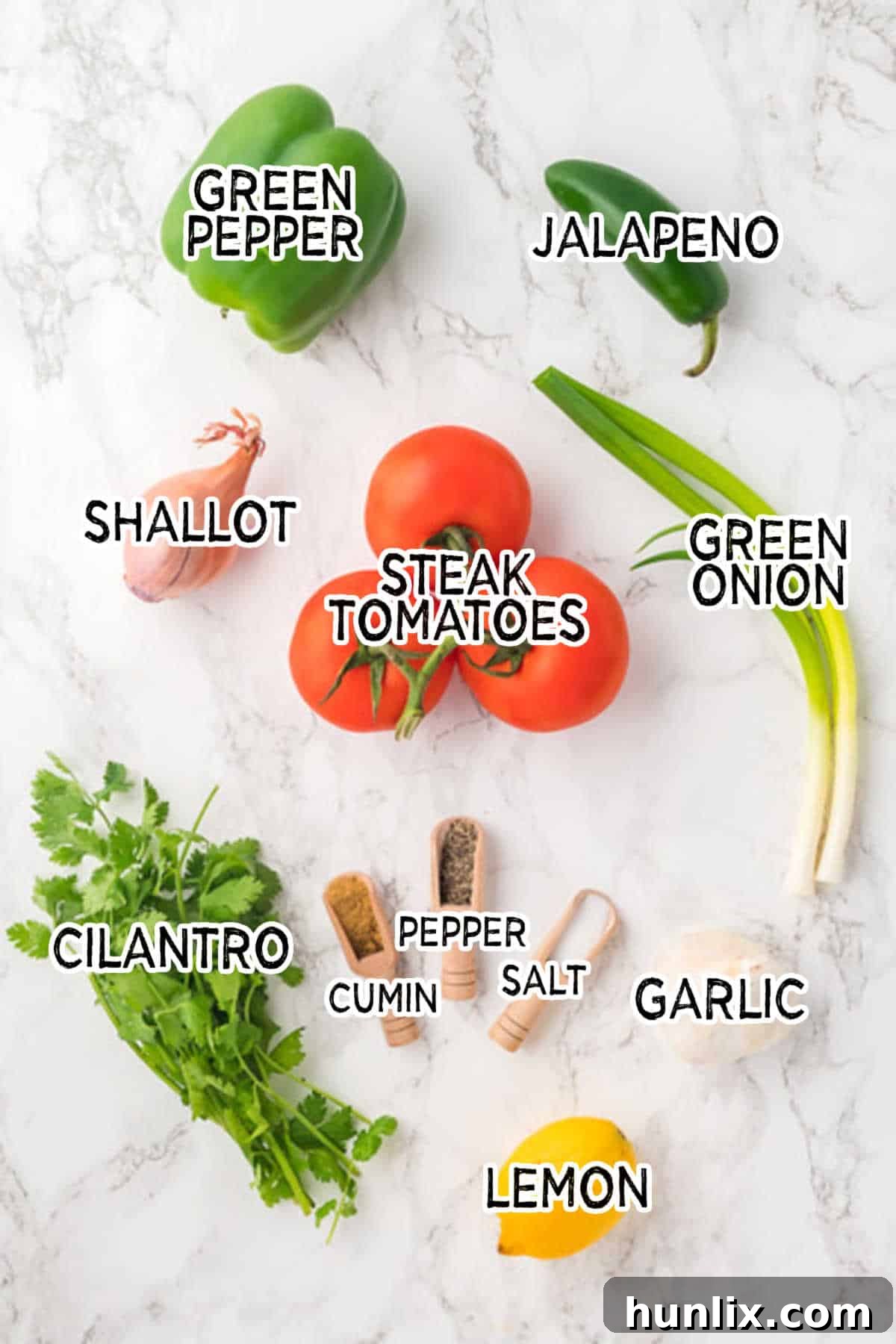A vibrant collection of fresh garden salsa ingredients, including red tomatoes, green peppers, a jalapeno, and fresh herbs, arranged on a wooden board.