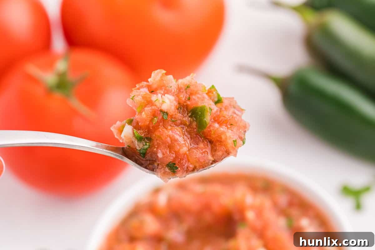 A close-up of chunky, fresh garden salsa scooped onto a spoon, ready to be enjoyed.