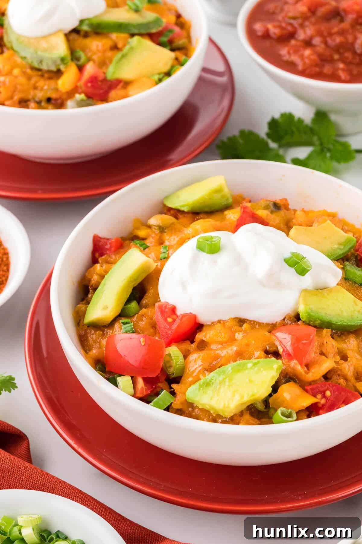 A bowl of hot one-pot chicken fajita rice, garnished with green onions and avocado.