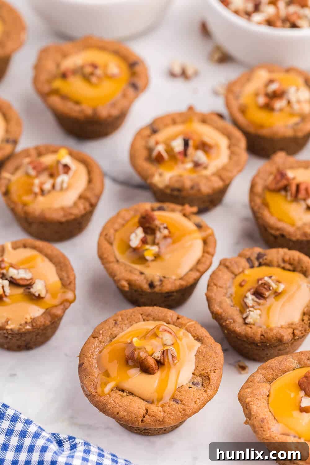 Caramel Stuffed Cookie Cups 2 caramel cookie cups on a white surface, showcasing their golden-brown edges and luscious caramel filling