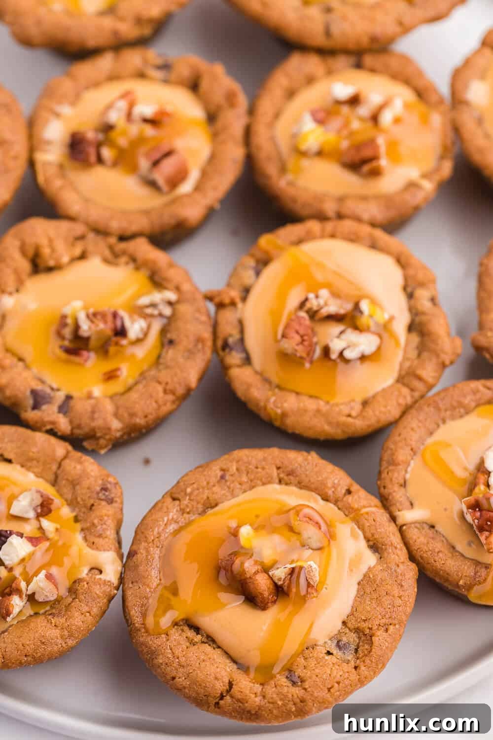 Caramel Stuffed Cookie Cups 5 multiple caramel cookie cups on a white plate, some topped with nuts