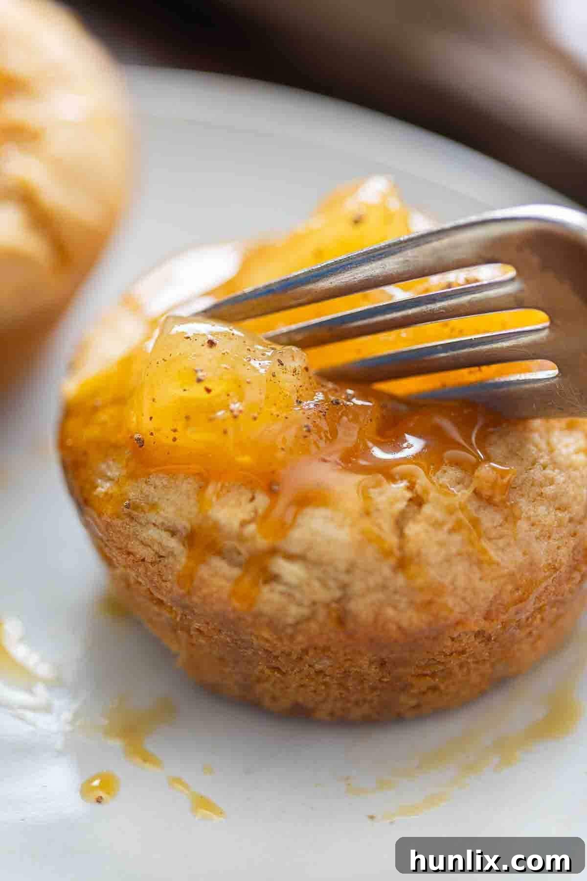 A Caramel Apple Cake Cup on a plate, cut open to reveal the apple and caramel filling.